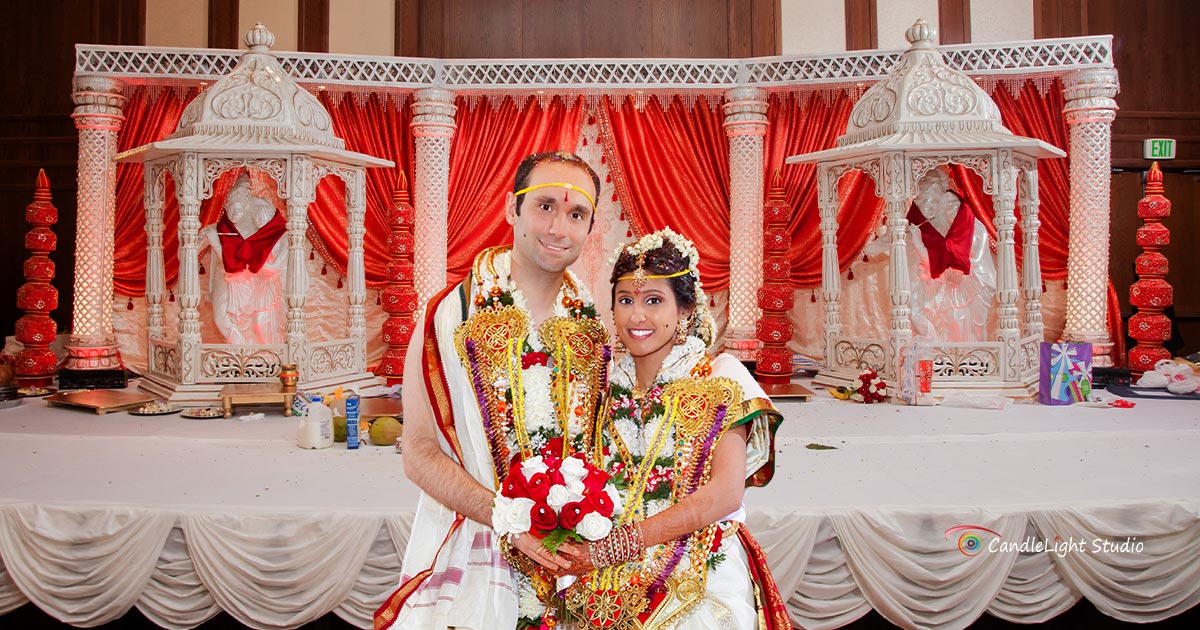 South Asian couple in traditional attire being photographed at their wedding.